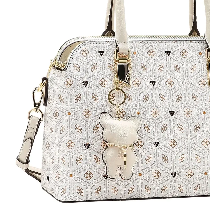 Close frontal da bolsa Chenson off white com chaveiro ursinho e acabamento brilhante